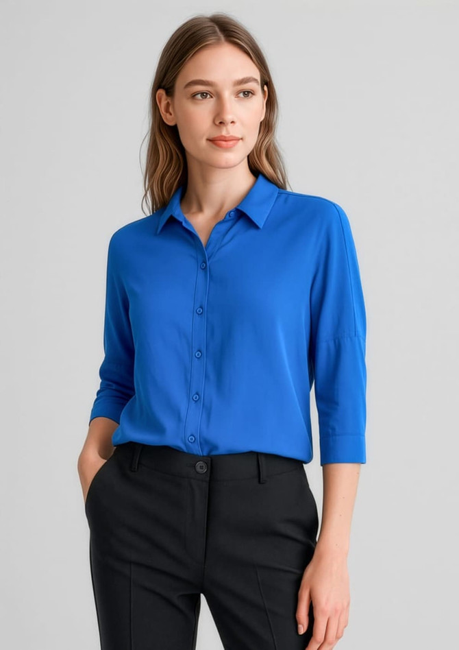 A vibrant blue 3/4 sleeve blouse with a collar and buttons, paired with black trousers.