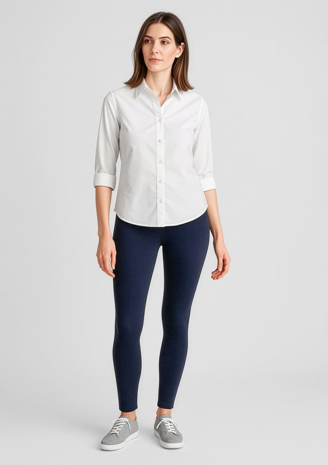 A woman stands wearing a white shirt and navy high-rise pull-on leggings, paired with grey shoes. The image includes a logo.