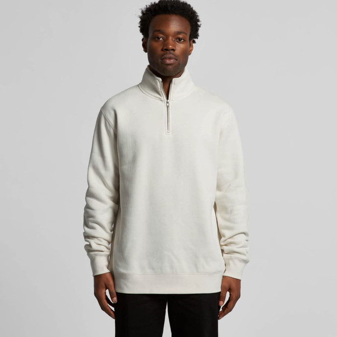 A man is wearing a cream-coloured half zip crew jumper with a relaxed fit, featuring a stand-up collar.