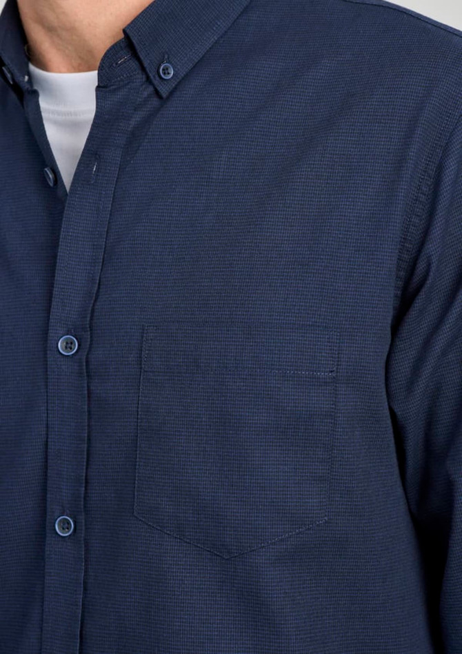 A navy blue long sleeve button-up shirt featuring a single chest pocket and a collar, complete with branding.