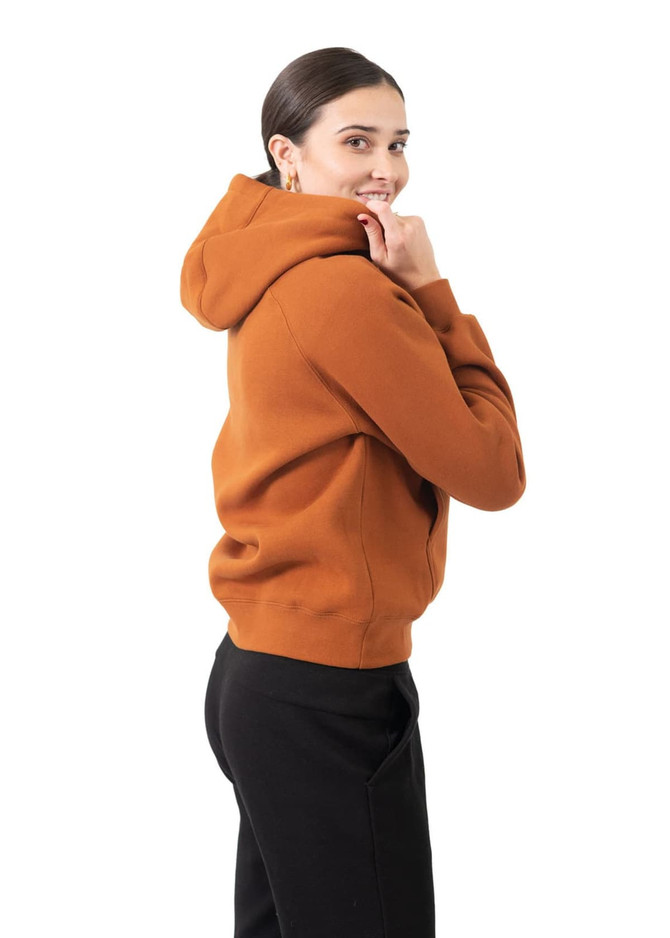 A woman smiles while wearing a burnt orange cotton hoodie with a kangaroo pocket and a logo.