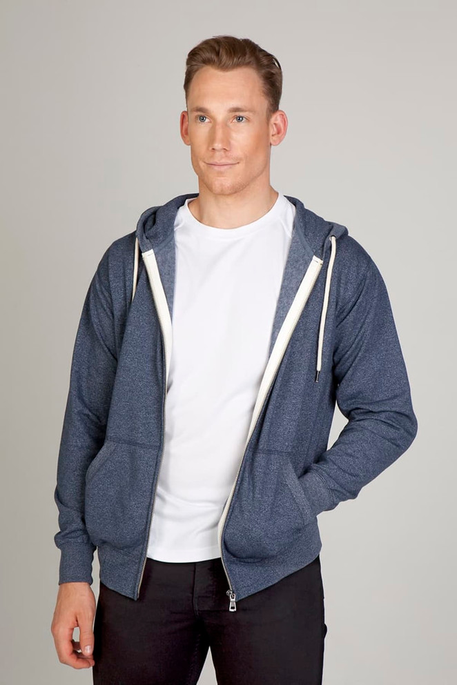 A blue heather zip hoodie with a front pocket and hood, worn over a white T-shirt. The model is standing against a neutral background.