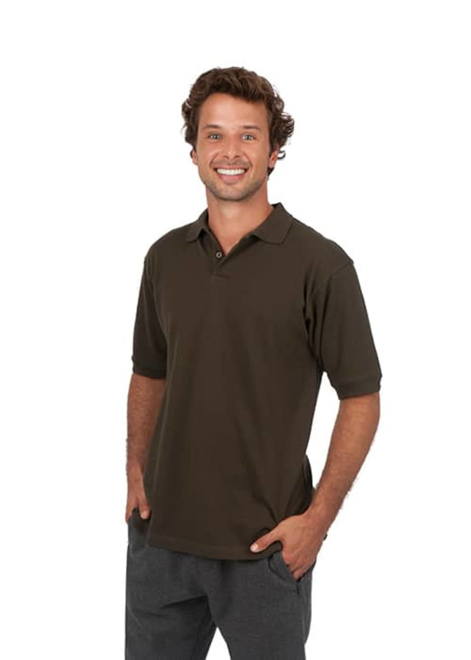A man wearing a dark green cotton polo shirt with a logo, posing casually with hands in pockets.