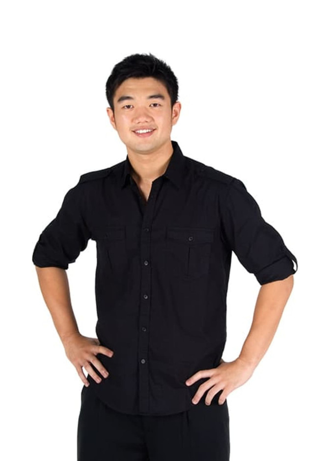 A black men's military long sleeve shirt with button-up front and two chest pockets. The model poses with hands on hips.