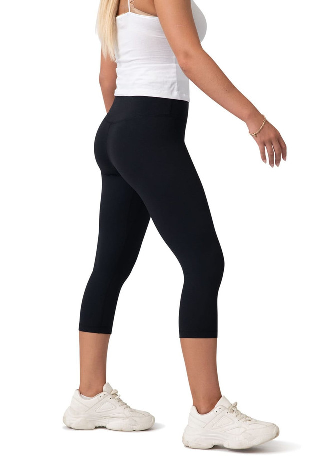 Black high-rise 3/4 leggings displayed on a model, paired with white sneakers. The image features a logo.
