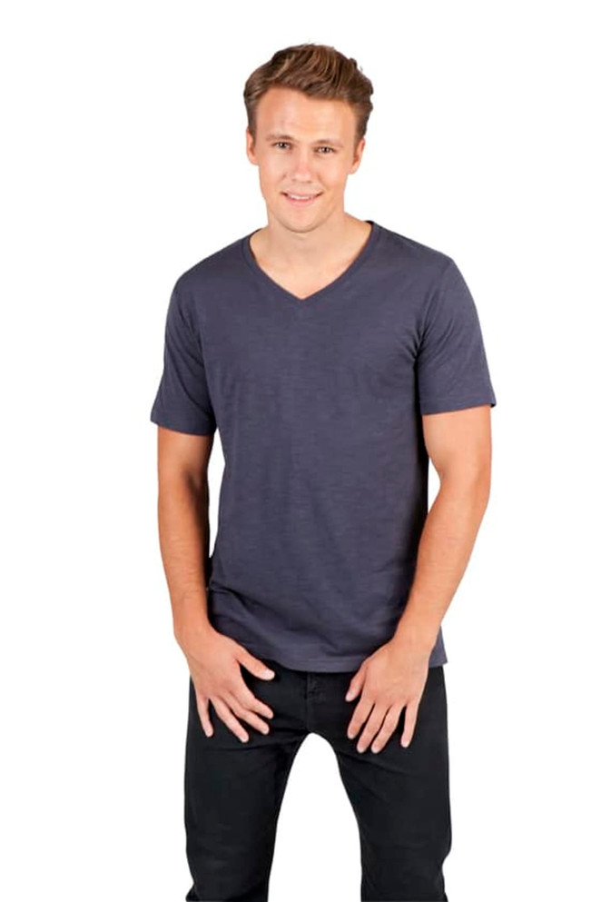 A man poses in a navy raw cotton V-neck T-shirt, paired with black jeans. The shirt has a branding logo.