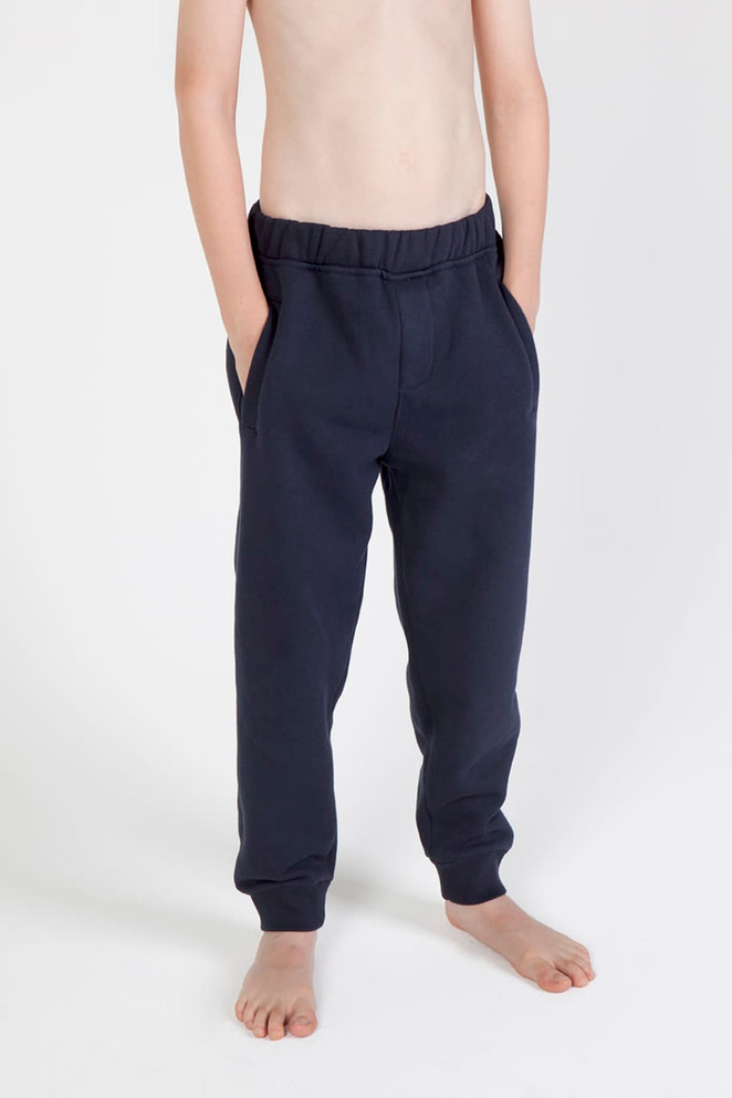Junior track pants in navy, featuring an elastic waistband and side pockets, displayed on a bare torso.