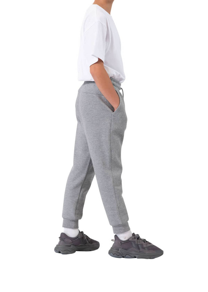 A pair of grey three-layer cotton track pants with side pockets, modelled by a person wearing a white t-shirt and sneakers.