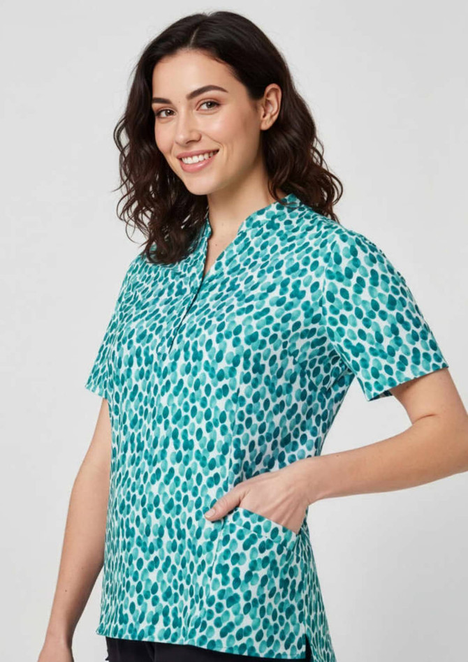 A tunic featuring a teal and white stardust print, with short sleeves and a pocket, displayed on a model.