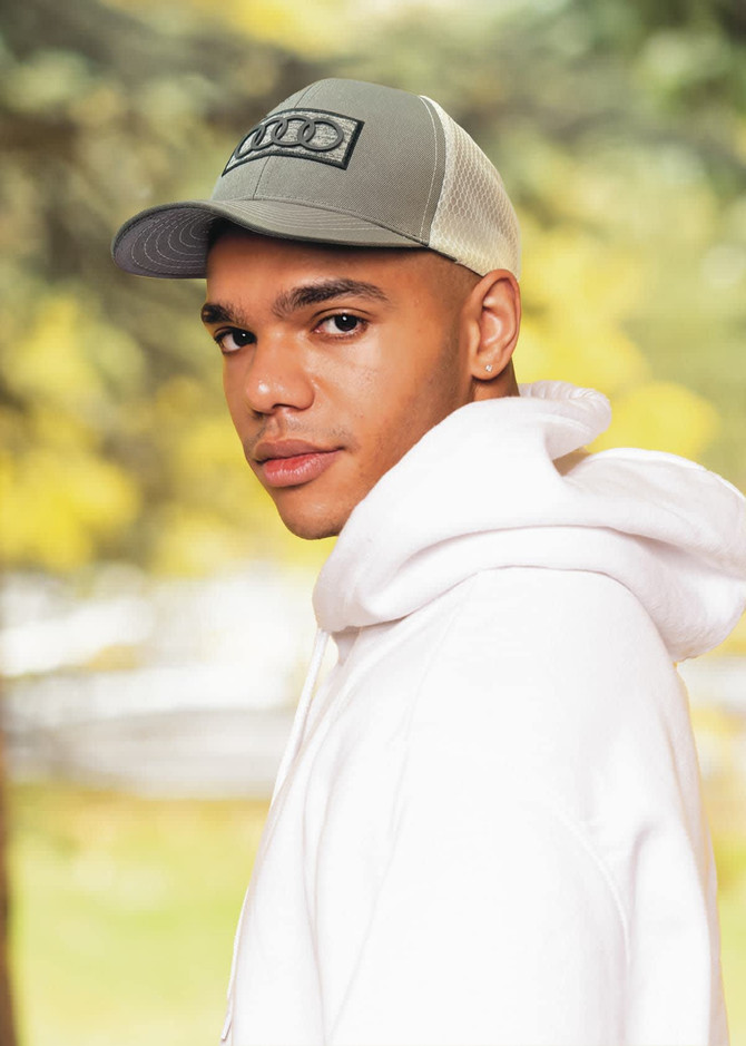 A breathable grey poly twill cap with honeycomb mesh, featured on a model wearing a white hoodie.