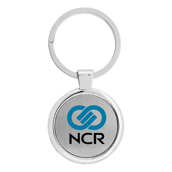 A silver keychain featuring a circular design with a branding logo on a metal surface.