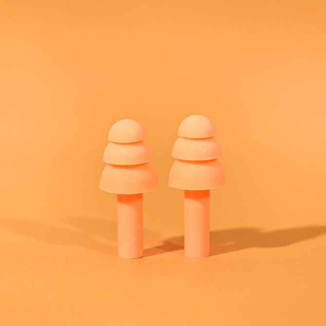 A pair of peach silicone earplugs on an orange background, designed for noise reduction, featuring a simple and smooth shape.