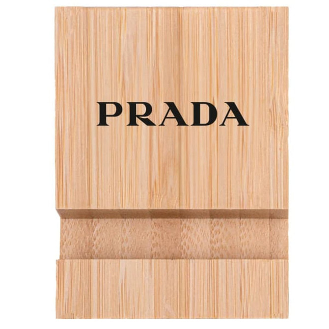 A bamboo phone holder in a natural wood finish featuring a logo on the front.