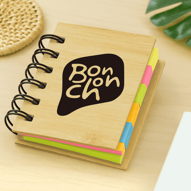 A mini bamboo sticky note set featuring various coloured sticky notes, bound with a spiral. The cover has a logo. A mini bamboo sticky note set featuring various coloured sticky notes, bound with a spiral. The cover has a logo.