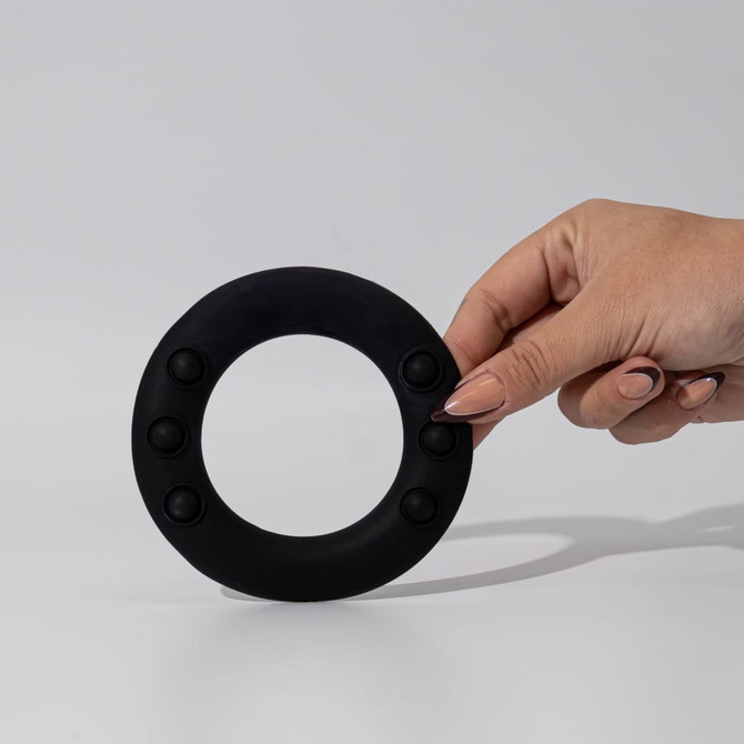 A black silicone wrist disc held by a hand, featuring several raised buttons around its edge.