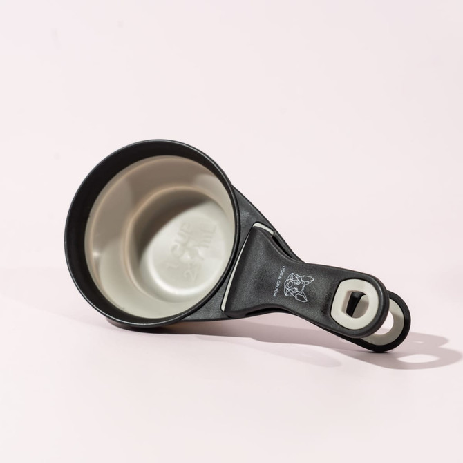 A black and grey collapsible silicone pet food scoop with a bag clip, featuring a logo. A black and grey collapsible silicone pet food scoop with a bag clip, featuring a logo.