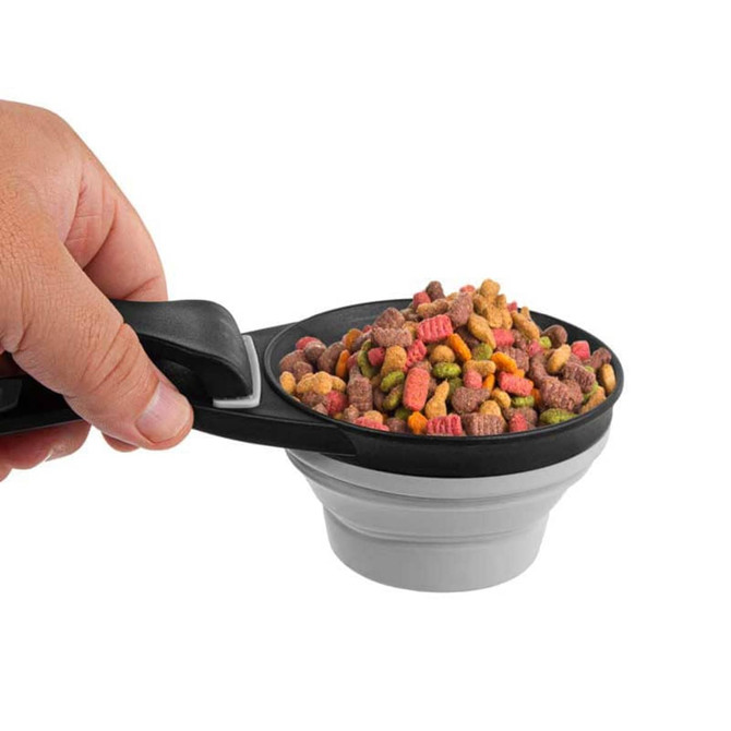 A collapsible silicone pet food scoop in black and grey, filled with colourful pet food, held in a hand. A collapsible silicone pet food scoop in black and grey, filled with colourful pet food, held in a hand.