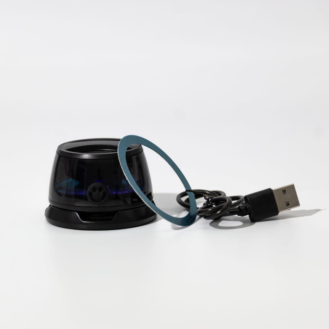 A compact black speaker with a blue accent ring and a USB cable. It features a sleek, modern design.