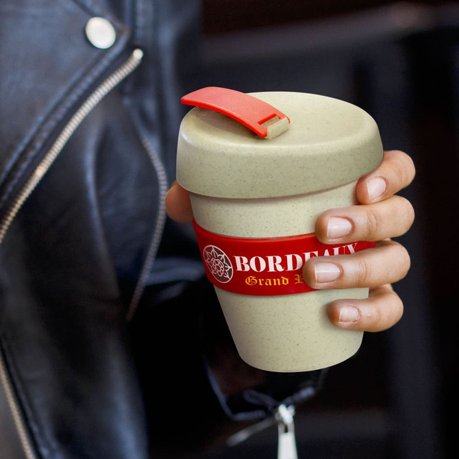 A drink bottle in a light green colour with a red band and a red lid. It features a logo.