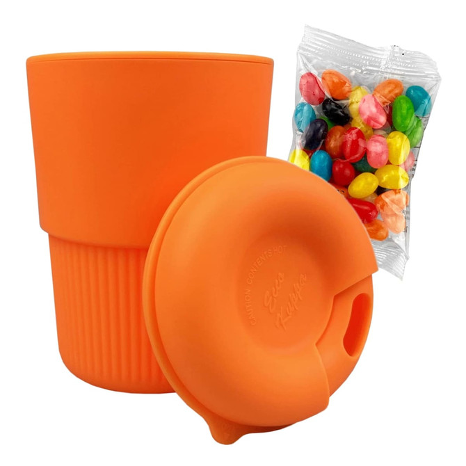 A reusable coffee cup in vibrant orange silicone, accompanied by a bag of colourful jelly beans.