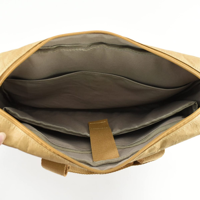 An interior view of a tan kraft paper business satchel with compartments and a zip closure. It features a soft lining.