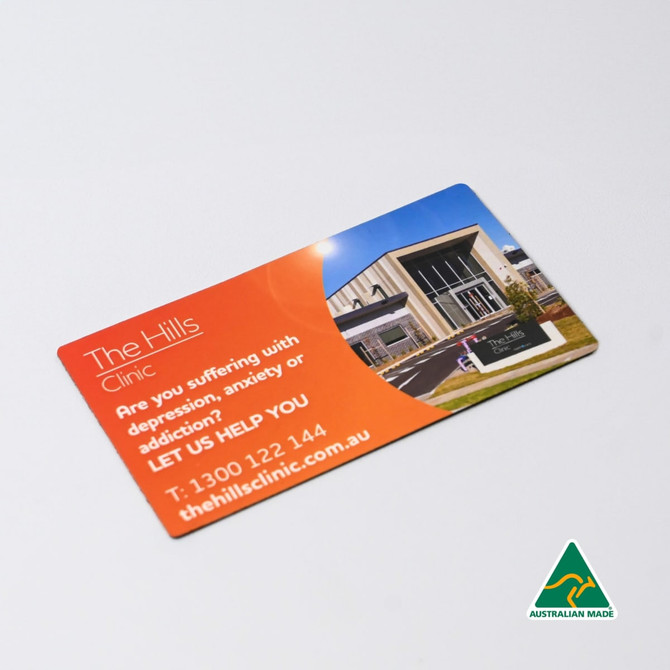A rounded-corner fridge magnet featuring a vibrant design with an image of a building and a logo.