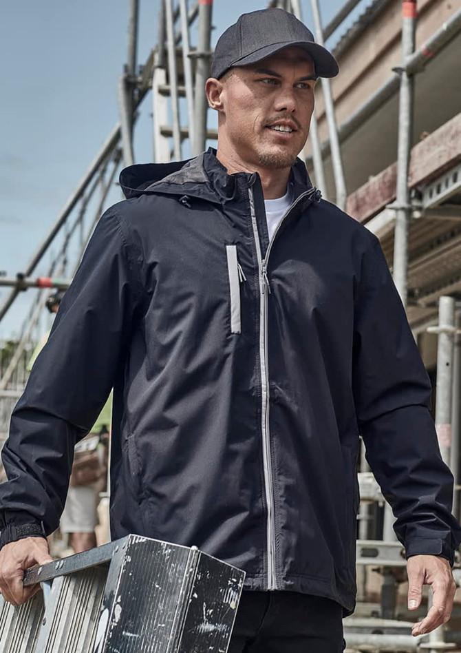 A man wearing a black unisex packable rain jacket, holding a metal ladder, with construction scaffolding in the background.