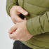 A close-up of a person wearing a green thermal jacket, focusing on the cuff and zip area, with a logo visible.
