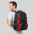 A man wearing a black and red outdoor backpack, showcasing mesh side panels and adjustable straps.