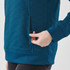 A close-up of a women's teal pullover with a quilted texture and side pocket detail.