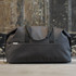 A black duffle bag with rounded edges, featuring an exterior pocket and a logo.