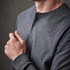 A grey long-sleeve Henley shirt with a two-button placket and fitted sleeves. It features a subtle logo.