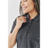 A woman wearing a charcoal grey women's polo shirt, smiling and adjusting the collar. The shirt features buttons and a logo.