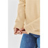A close-up of a woman wearing a beige fleece pullover hoody, showing the cuff detail and her hands.