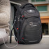 A black Swissdigital Neptune Backpack with multiple pockets, zippers, and a logo. An earphone cable is attached.