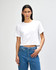 A white boxy women's t-shirt features short sleeves and a cropped design. The model pairs it with blue jeans.