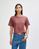 A women's boxy t-shirt in a dusty rose hue, featuring short sleeves and a relaxed fit, paired with blue jeans.