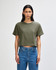 A women's boxy t-shirt in olive green, featuring a round neckline and short sleeves, styled with blue jeans.
