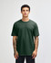 A unisex heavyweight cotton T-shirt in a dark green colour, displayed on a model with curly hair.