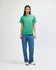 A green heavyweight cotton unisex T-shirt displayed on a model, paired with light blue cargo pants.