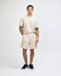 Beige unisex pique gym shorts displayed on a model, paired with a matching short-sleeve top and black sneakers.