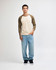 A unisex raglan T-shirt in cream with brown sleeves, paired with light blue cargo pants. Features a logo.