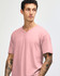 A pale pink unisex V-neck T-shirt on a model with tattoos, featuring a logo on the sleeve.