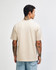 A light beige, unisex heavyweight t-shirt featuring a plain back design. It has a logo on the garment.