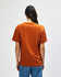 A man wearing an orange American Apparel Super Heavyweight T-Shirt, viewed from the back, with short sleeves.