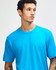 A unisex fine jersey short sleeve t-shirt in bright blue, paired with khaki pants. The model stands straight with a neutral expression.