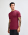 A unisex fine jersey short sleeve t-shirt in burgundy, featuring a logo, displayed on a male model from the side.