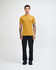 A model wearing a mustard yellow unisex short sleeve t-shirt paired with light blue baggy jeans and black shoes.