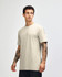 A unisex beige CVC short sleeve T-shirt displayed on a model, featuring a logo.