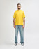 A man wearing a bright yellow Gildan Softstyle adult T-shirt and grey jeans, standing casually.